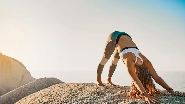 A woman stretching above the sea at sunrise