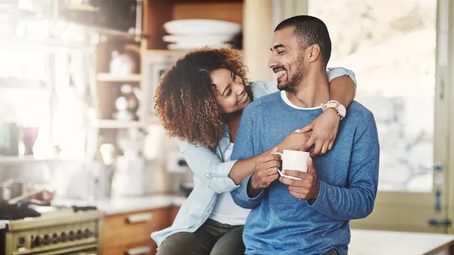 A couple laughing together over coffee at home